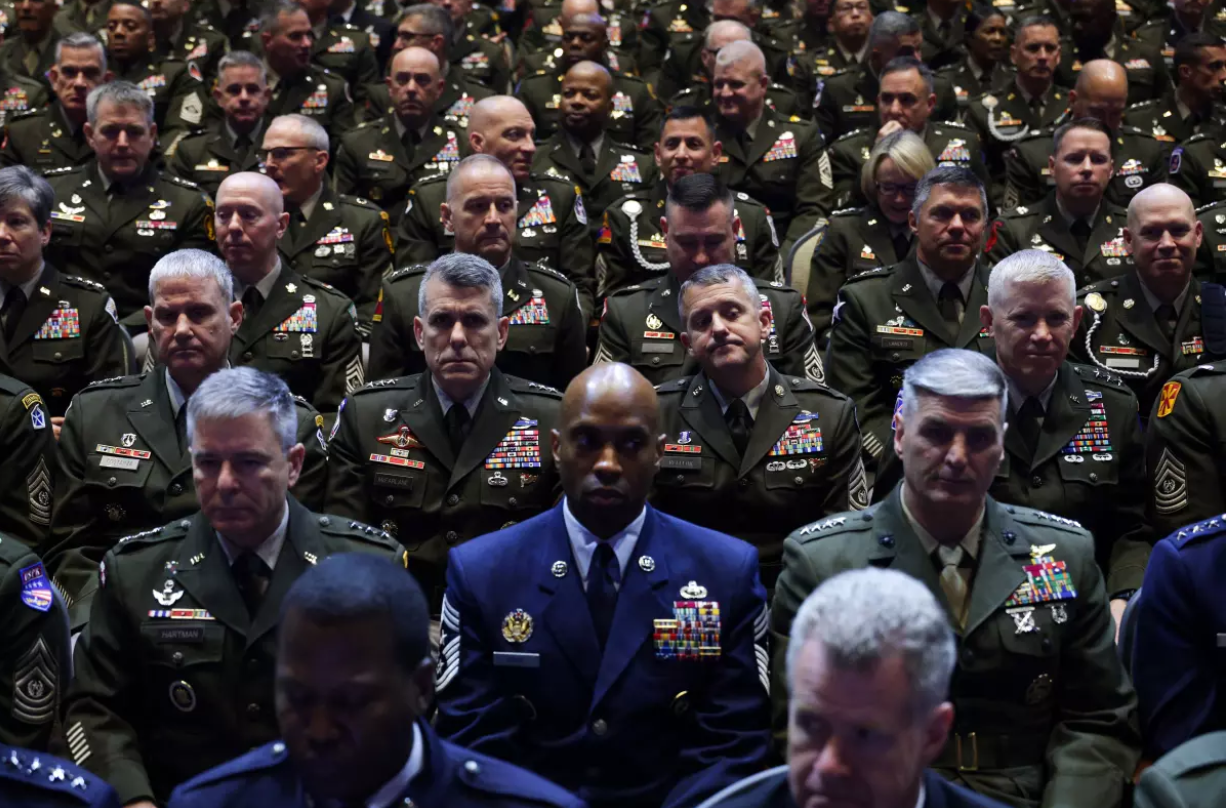 Generals and Admirals listening to the Secretary of "My Daddy Didn't Hug Me Enough"'s rant about ending the "woke" military.  (A crowd of almost exclusively white men in military uniforms staring mostly stone-faced in the audience of a speech.)