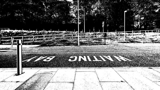 Black and white photo of a road with a marked place with the word waiting bay upside down from where I was sitting having a coffee. It's only Tuesday, the working week is so long................. Roll on the weekend. The text on my toot says 'waiting for the weekend' but upside down.