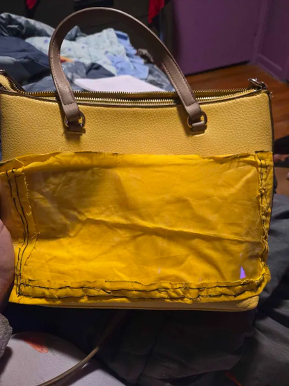 A yellow leather purse with a cloth pocket sewn onto it.