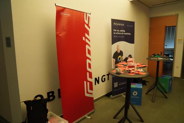 The logos of our Fronius and Dynatrace and tables with goodies / swag.