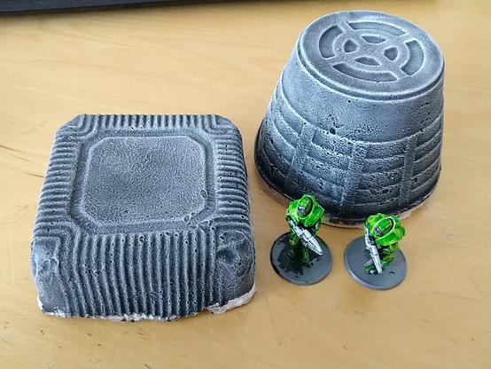 The two terrain pieces next to each other, along with two partially painted SciFi soldiers for scale. The slab is just a bit lower than a mini, and the cone is almost twice as tall.
