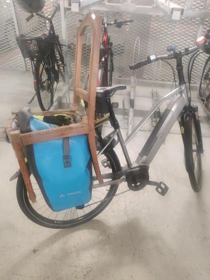 Un vélo sur le porte-bagage duquel est attachée une ancienne chaise en bois