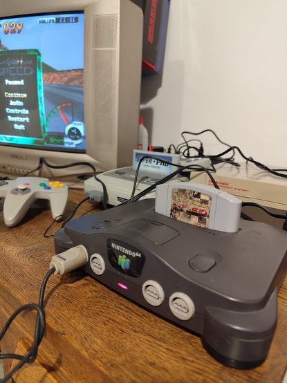 consola nintendo 64 junto con un super famicom y un nintendo nes al lado de una tv crt