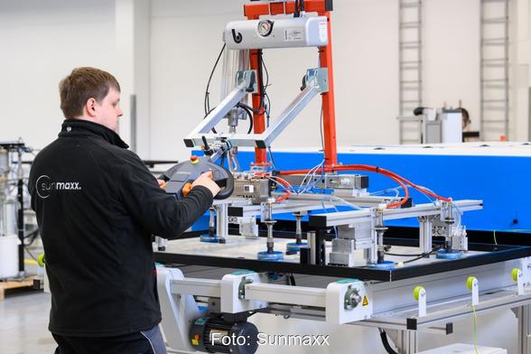 Sunmaxx-Mitarbeiter in Fabrikhalle an einem Arbeitstisch mit PVT-Modul.
