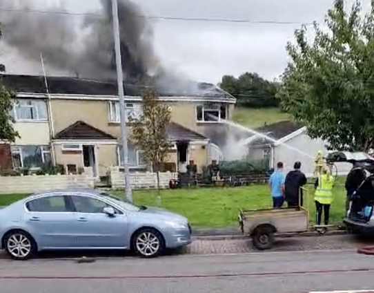Mid and West Wales Fire and Rescue Service crews tackle the Neath house fire on Furnace Terrace, using hose reels to fight flames inside the two‑storey end‑terrace home.