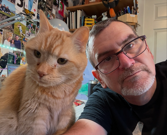 An orange cat and a nerd take a selfie.