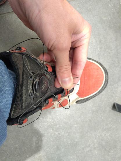 Bild von meinem Schuh mit Boa Verschlussystem.
Die Schnürsenkel, was ein Draht in Plastikmantel ist, ist gerissen und ich halte beide Enden in der Hand