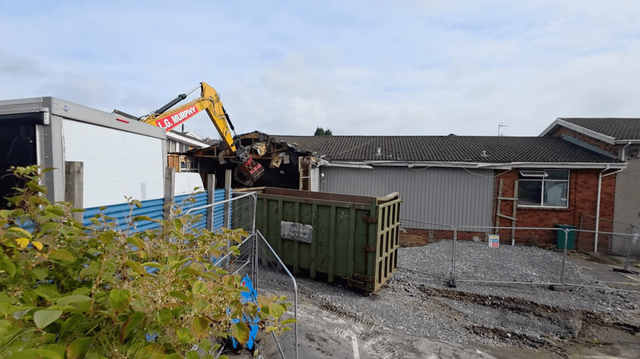 Demolition begins at Cwmfelin Social Club in Cwmbwrla, Swansea, as heavy machinery tears into the roof of the building above the sinkhole site.