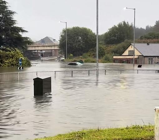 File photo shows vehicles submerged at Cwmbwrla roundabout in Swansea during September 2025 flooding, later linked to the collapsed culvert beneath Cwmfelin Social Club.