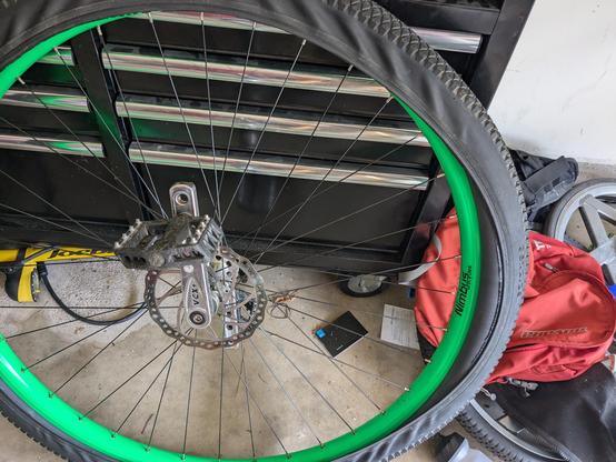 A tire halfway onto a green 36" unicycle wheel