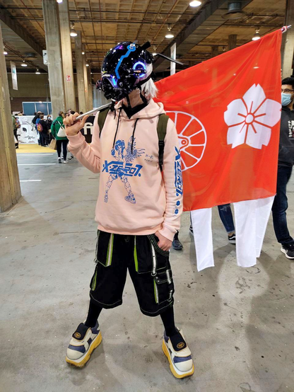 Full shot of me in a comic con bearing my personal flag. I'm wearing a pink hoodie with a blue cyber angel girl, black short pants with neon and silver details, chunky white, blue and cream shoes, my legs fully covered in black. My head is hidden under a cyber helmet with all sorts of pieces and lights in blue. My hair is long and white.

The flag I'm bearing is a red square with a cherry blossom and a train wheel in white, and there are four white tails in the fly.