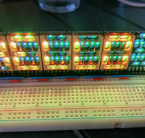 a 16-segment display RGB-LED prototype in a breadboard, BG is turquoise, "HELLO" is visible in bright warm yellow to orange