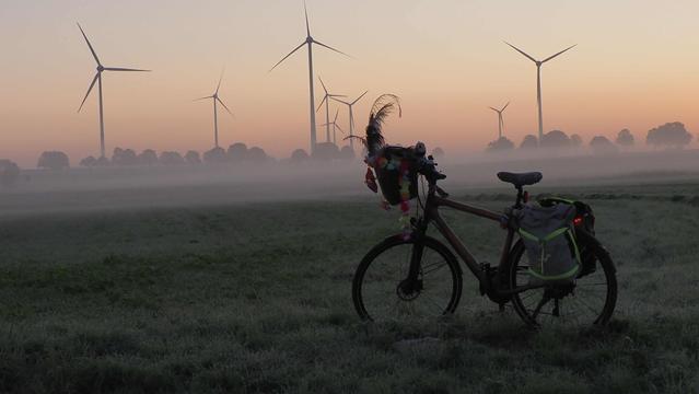 Fahrrad im Morgenlicht, im Hintergrund Windräder