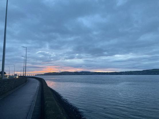View across Tay Firth as the early mot sun breaks on the horizon glowing pink through the dull grey