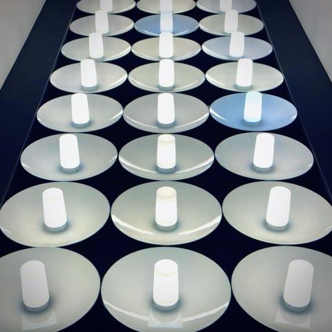 A grid of saucer-lamped bulbs trails off in the distance, with each bulb a semi-tungsten hue, except two.
