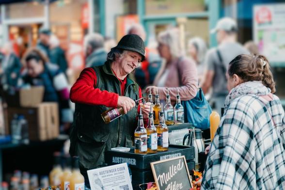 Austringer Cider stallholder pouring a sample for a customer at Neath Food and Drink Festival.
