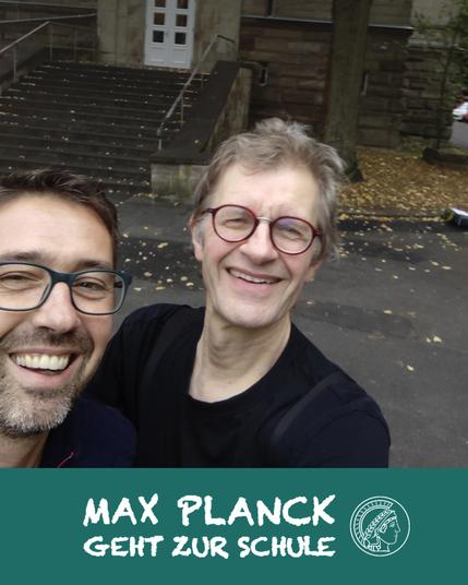 Selfie of a teacher and a scientist in front of a school