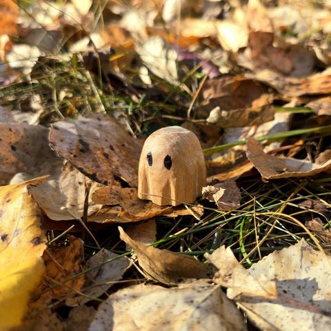 a wood carved ghost amongst leaves