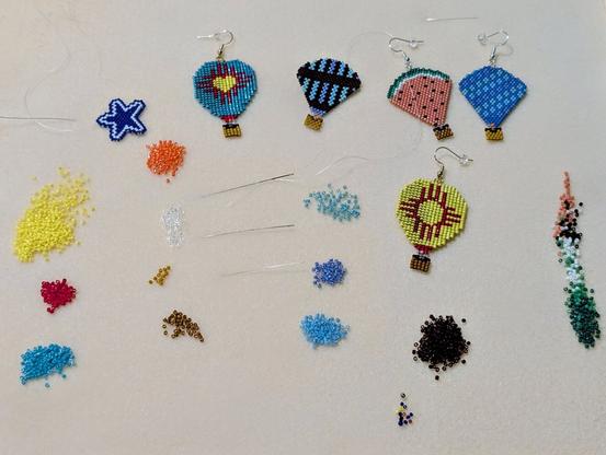A beading board filled with some of my current projects: hot air balloon earrings in different styles and designs along with their matching loose delica beads. There is also a random blue and white star that was a tester for Dallas Coyboys earrings. It's just chilling though because the sale fell through. *sad noises*