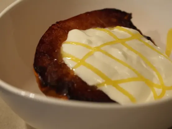 eine gebackene Quittenhälfte gefüllt mit griechischem Joghurt und beträufelt mit etwas Honig