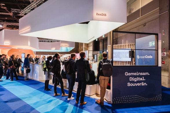 Menschen stehen vor dem Messestand des ZenDiS. Der Schriftzug "Gemeinsam. Digital. Souverän" ist zu lesen.