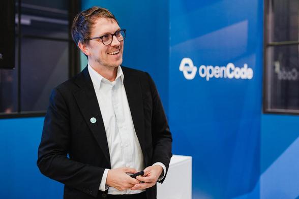Leonhard Kugler vor dem openCode-Logo.