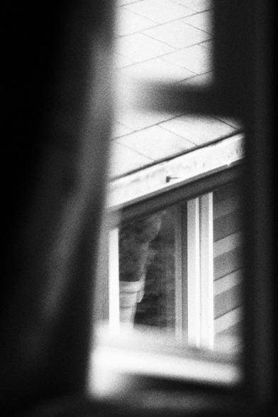 Looking down through a gap in a curtained window at a window in a garage.