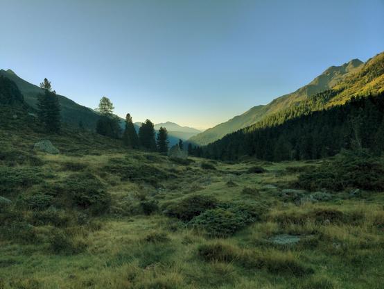 Green valley in the morning near Lienzer Hütte. The sun rises and only the bottom part of mountain sides are located in the shadows.