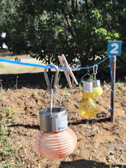 3 kleine Solar Led Lampions hängen auf einem an einen Pfosten gespannten Wäscheleine
