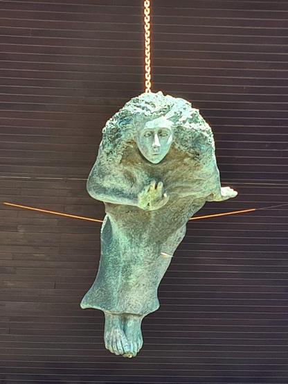 A large bronze statue suspended from a building.