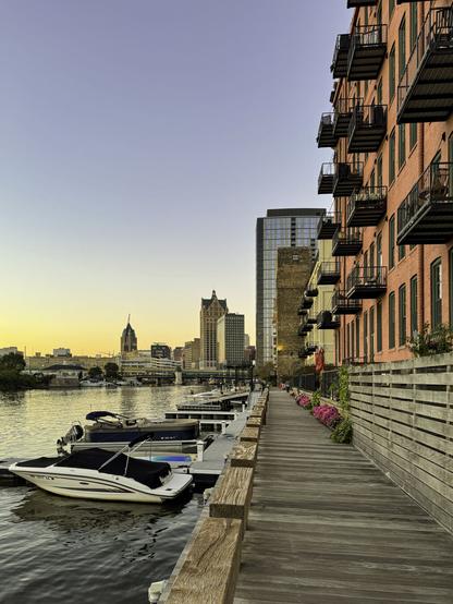 Public walkway along a river with historic buildings and boat docks