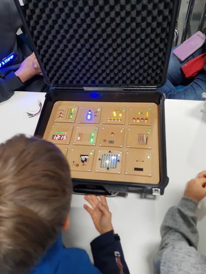 Kinderkopf von oben und ein "Bombenkoffer" mit vielen Schaltern und LEDs.