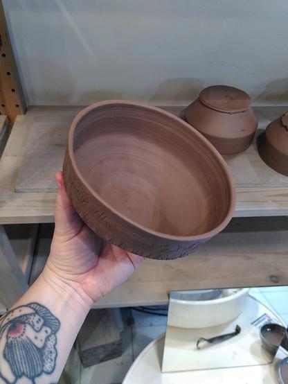Bol en terre crue fraîchement tournassé
Il est tenu en main par la potière 
Vue de l'intérieur