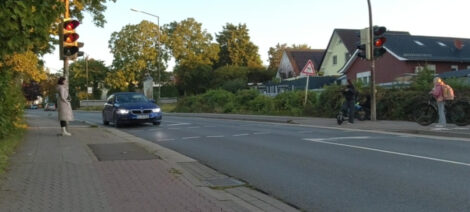Ein Auto ist mit den Vorderrädern an der Haltelinie einer ampelgestuererten Fußgängerquerung zu sehen. Die Ampel zeigt orange.
