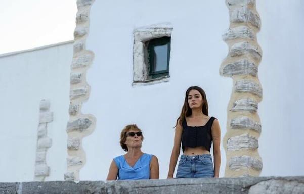 Fiona Shaw and Emma Mackey in Hot Milk. Shaw is seated with Mackey standing nearby. They are in front of a while building.