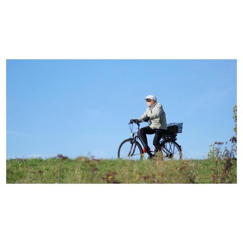Jemand radelt in gesteppter Jacke und dicker Winterleggings über den Deich am Falckensteiner Strand.