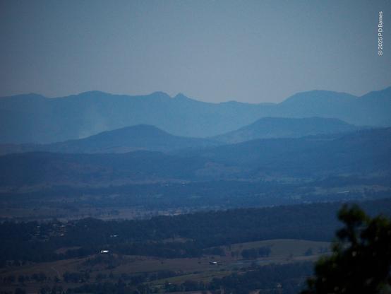 View over lightly wooded landscape past successive more distant ridge lines as the light becomes more and more blue and the details less and less distinct.