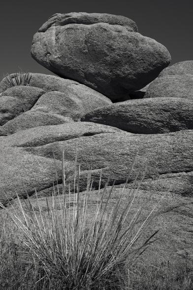 A large boulder nestles precariously atop a field of rocks.