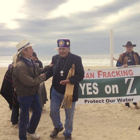 (Photo by Mari Lynch for BikeMonterey.org.) On Salinas River Beach, American Indian Movement (AIM) co-founder Dennis Banks, who came from the Dakota Access Pipeline to Monterey County on October 3, 2016. Banks spoke his endorsement of Measure Z, then held a Native American ceremony where the Salinas River meets the Monterey Bay. Behind Banks, volunteers hold a Protect Monterey County banner that reads “Ban fracking. Yes on Z. Protect our water. "
