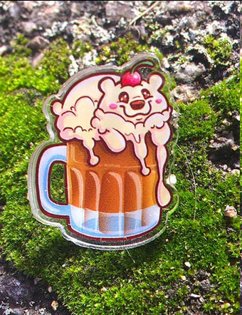 acrylic pin of a bear made out of root beer foam sitting on moss