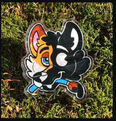 acrylic pin of a fox holding a paint brush and turning into a rubberhose toon against moss
