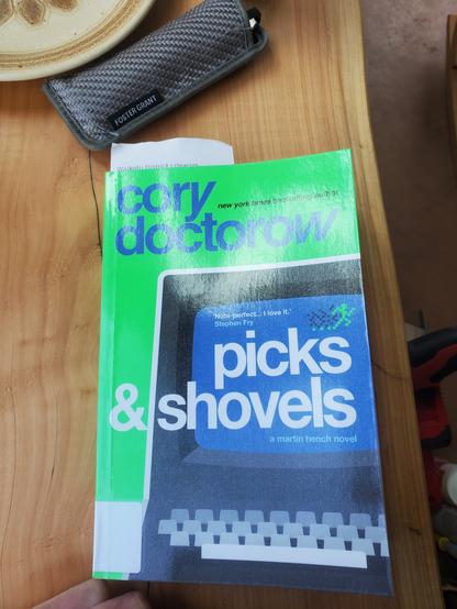 Novel on a wooden seat with library slip poking out.