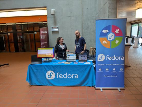 Stánek Fedory s modrým ubrousem a bannerem.