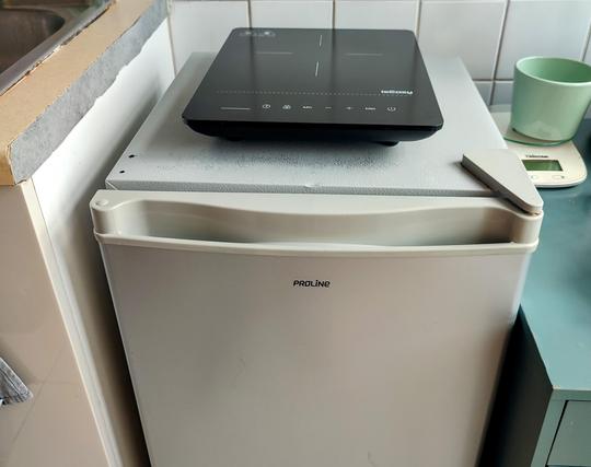 Photo très moche montrant un petit frigo et une taque de cuisson.