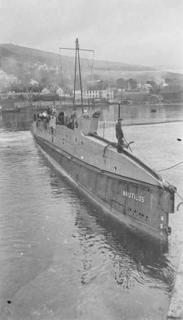 A black and white photo of a 1910s submarine, the Nautilus, docked up in Bergen.