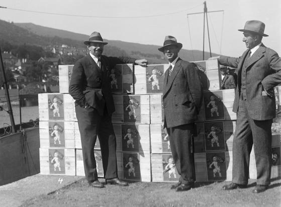 A black and white photo of three of the crew – wearing suits and hats – of the 1910s submarine, the Nautilus, docked up in Bergen.
