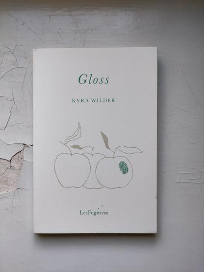 Kuvassa kirjan valkoinen kansi, jossa kolme piirrettyä omenaa. Yhdessä omenassa näkyy sormenjälki.