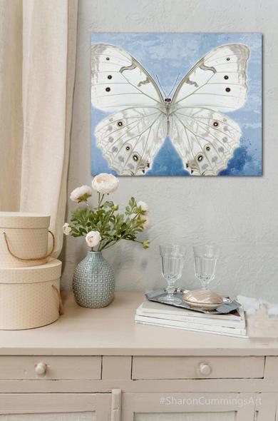White butterfly on muted blue watercolor art.  In a furniture setting by artist Sharon Cummings.