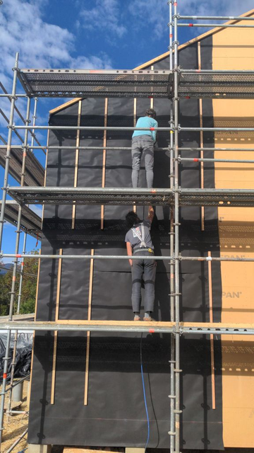 deux personnes posent du pare pluie sur une façade maison