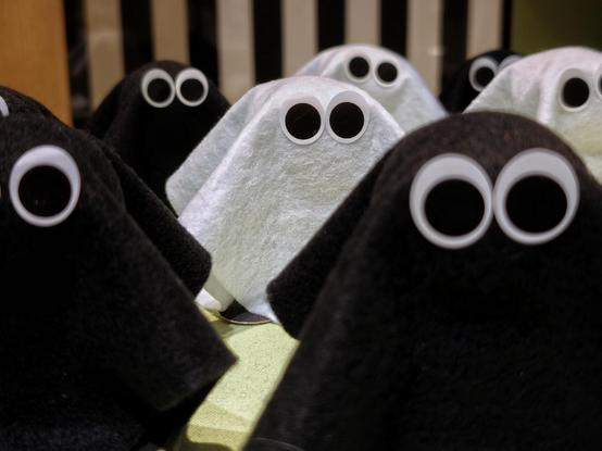 A photo showing a group of small black and white fabric figures with large googly eyes arranged closely together.